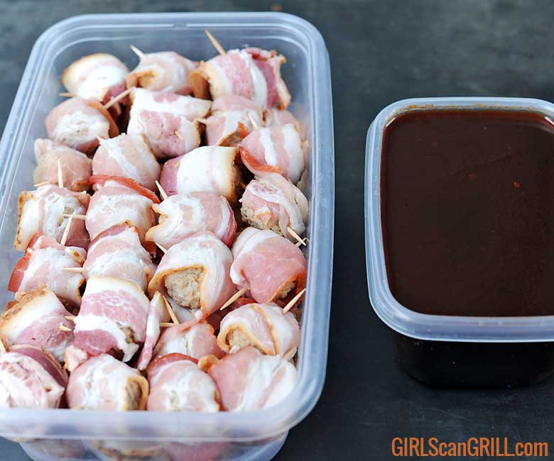 plastic container full of raw bacon-wrapped meatballs with bowl of sauce to right