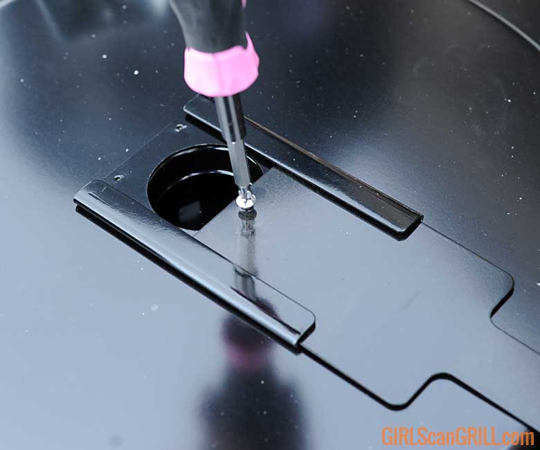 using a pink screwdriver to tighten a damper to a grill