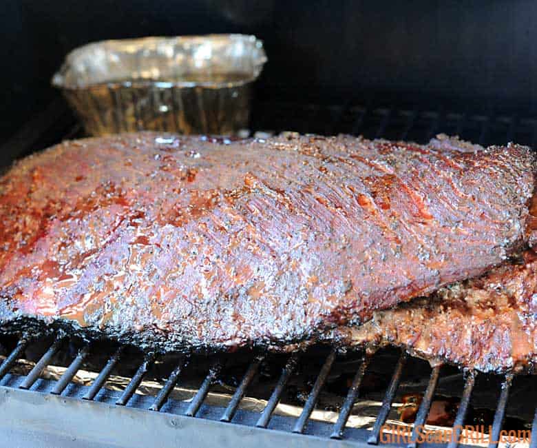 brisket smoking on grill with pan of water