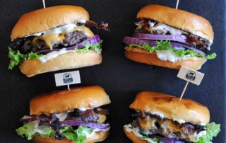 4 hamburgers on slate with lettuce, cheese and mayo