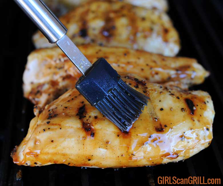 black brush basting sauce on a grilled chicken breast