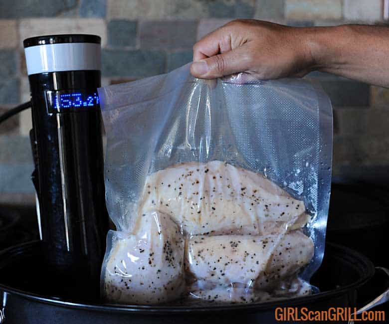 FoodSaver sous vide bag with chicken being dipped into pot of water