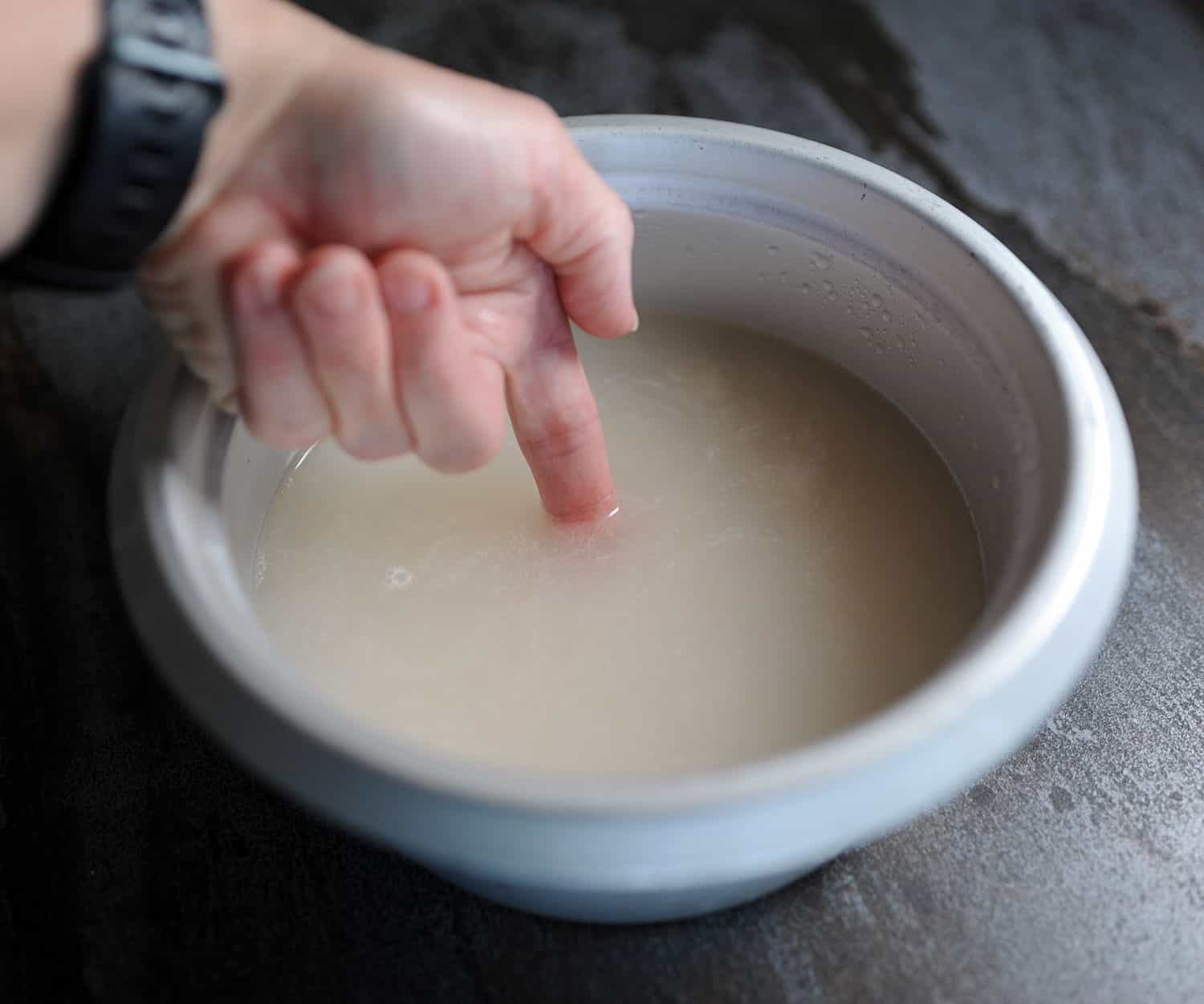 index finger in rice cooker with water up to first line on finger