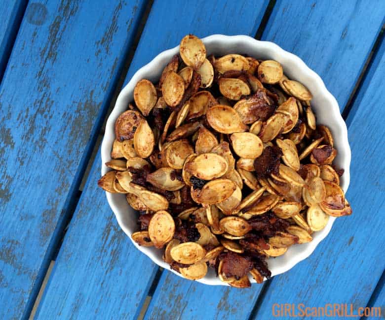 white bowl of smoked bacon pumpkin seeds on blue wooden table
