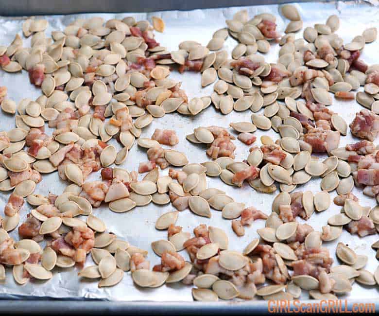 raw pumpkin seeds and bacon on foil covered sheet pan