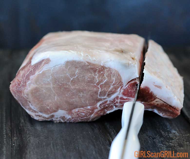 slicing down the top of the pork prime rib roast toward the bone