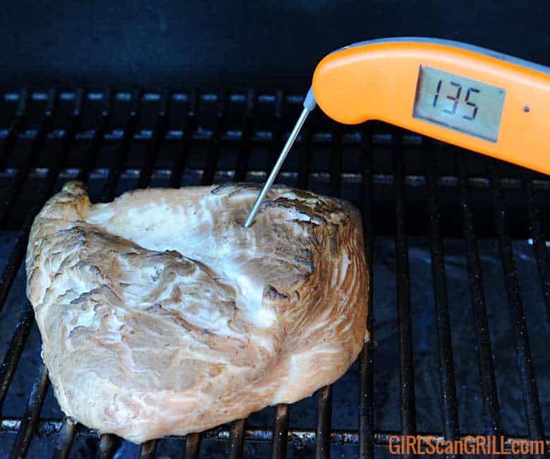 smoked turkey breast on grill with thermometer showing 135F.