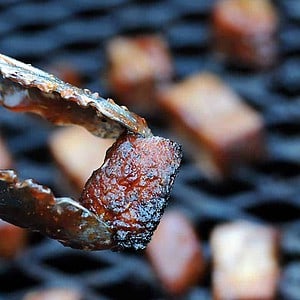 tongs holding smoked turkey burnt ends