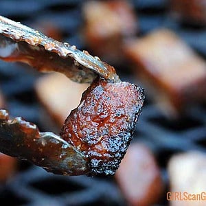tongs holding smoked turkey burnt ends