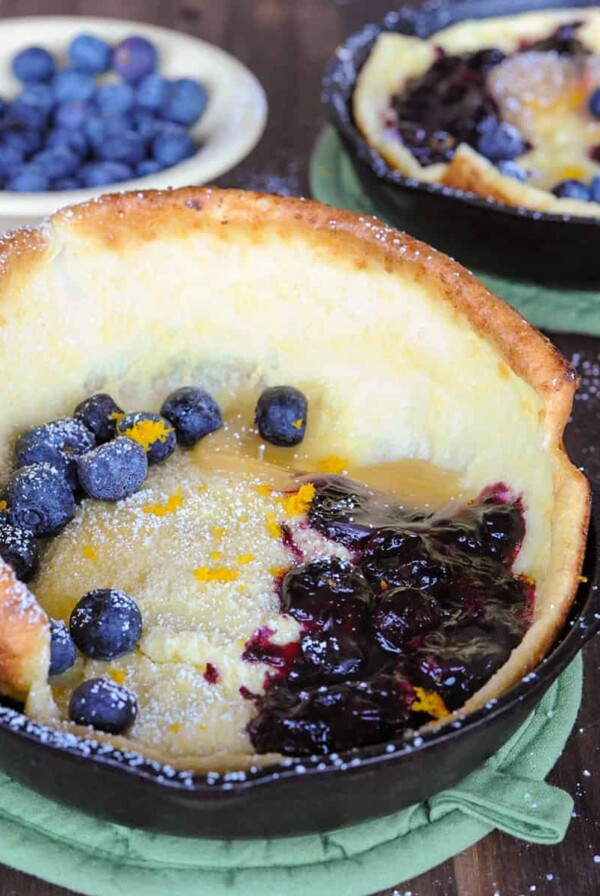 two dutch baby pancakes topped with blueberry compote and lemon curd.
