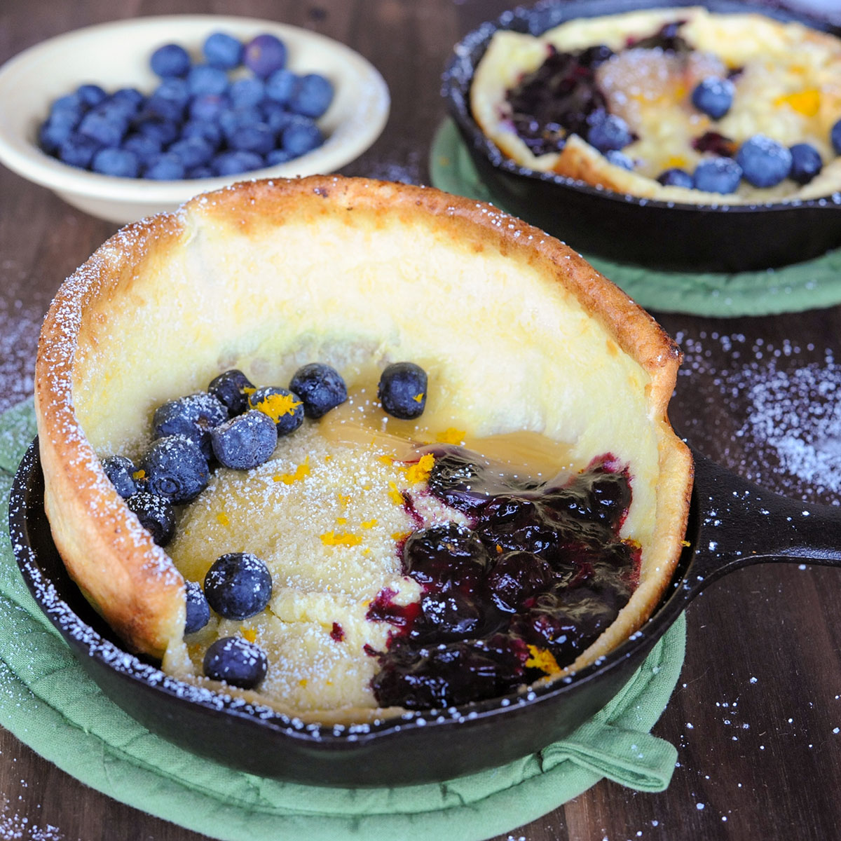 two dutch baby pancakes topped with blueberry compote and lemon curd.