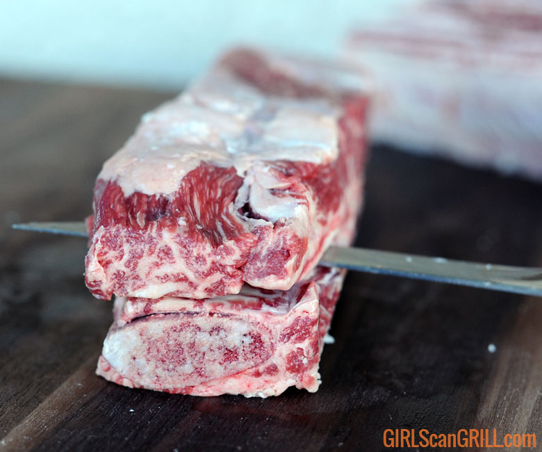sliding knife between bone and meat of short rib