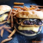 two double smoked smashburger cheeseburgers on a griddle surrounded by fries