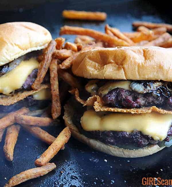 two double smoked smashburger cheeseburgers on a griddle surrounded by fries