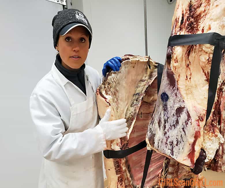 Female butcher showing parts of a cow.