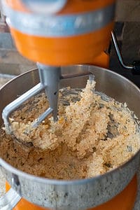 Mixing shredded cheeses into cream cheese with stand mixer.