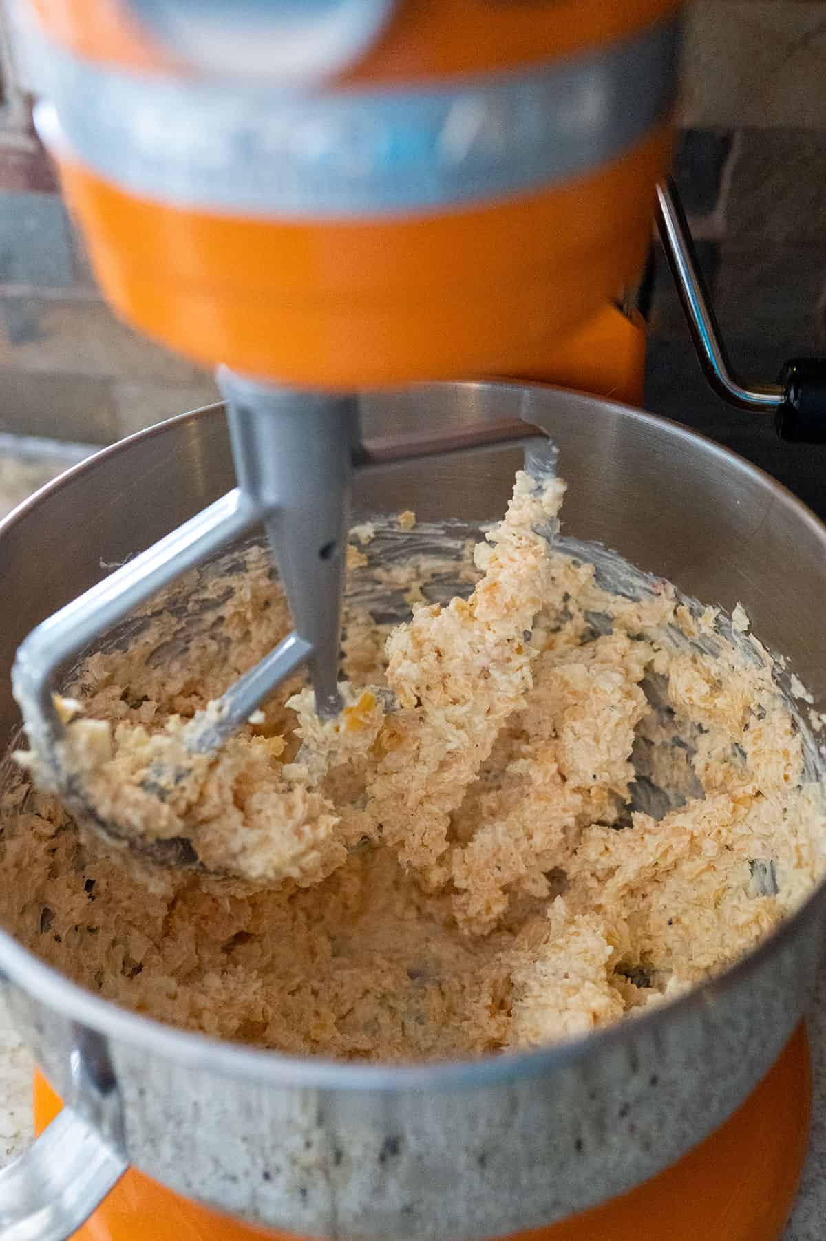 Mixing shredded cheeses into cream cheese with stand mixer.