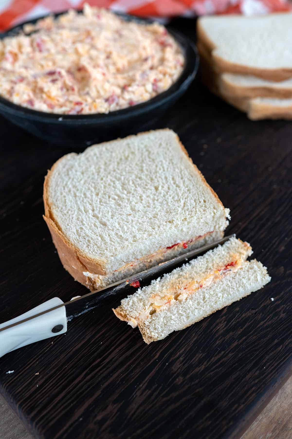 Cutting crust off of pimento cheese sandwich.
