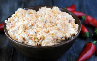 wooden bowl filled with pimento cheese surrounded by peppers