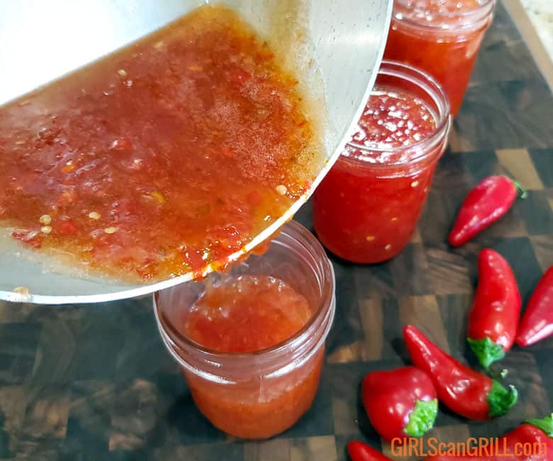 pouring red pepper jelly from pot to jar