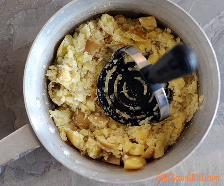 mashing yellow potatoes in a pot.