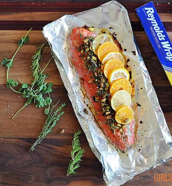 salmon fillet topped with citrus, herbs and nuts on foil
