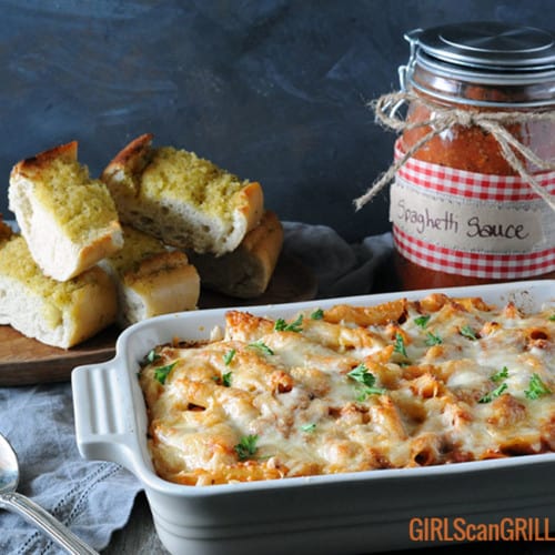 pasta casserole near jar of smoked homemade spaghetti sauce and garlic bread