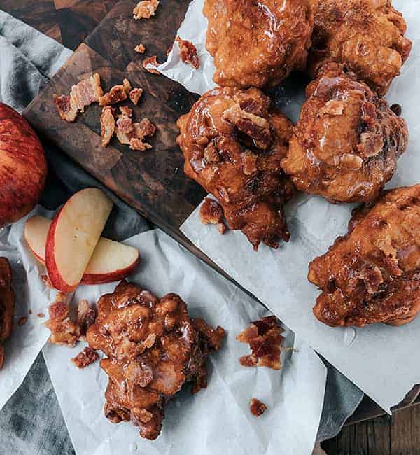 bacon apple fritters stacked on wooden platter