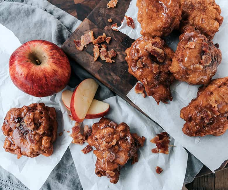 bacon apple fritters stacked on wooden platter