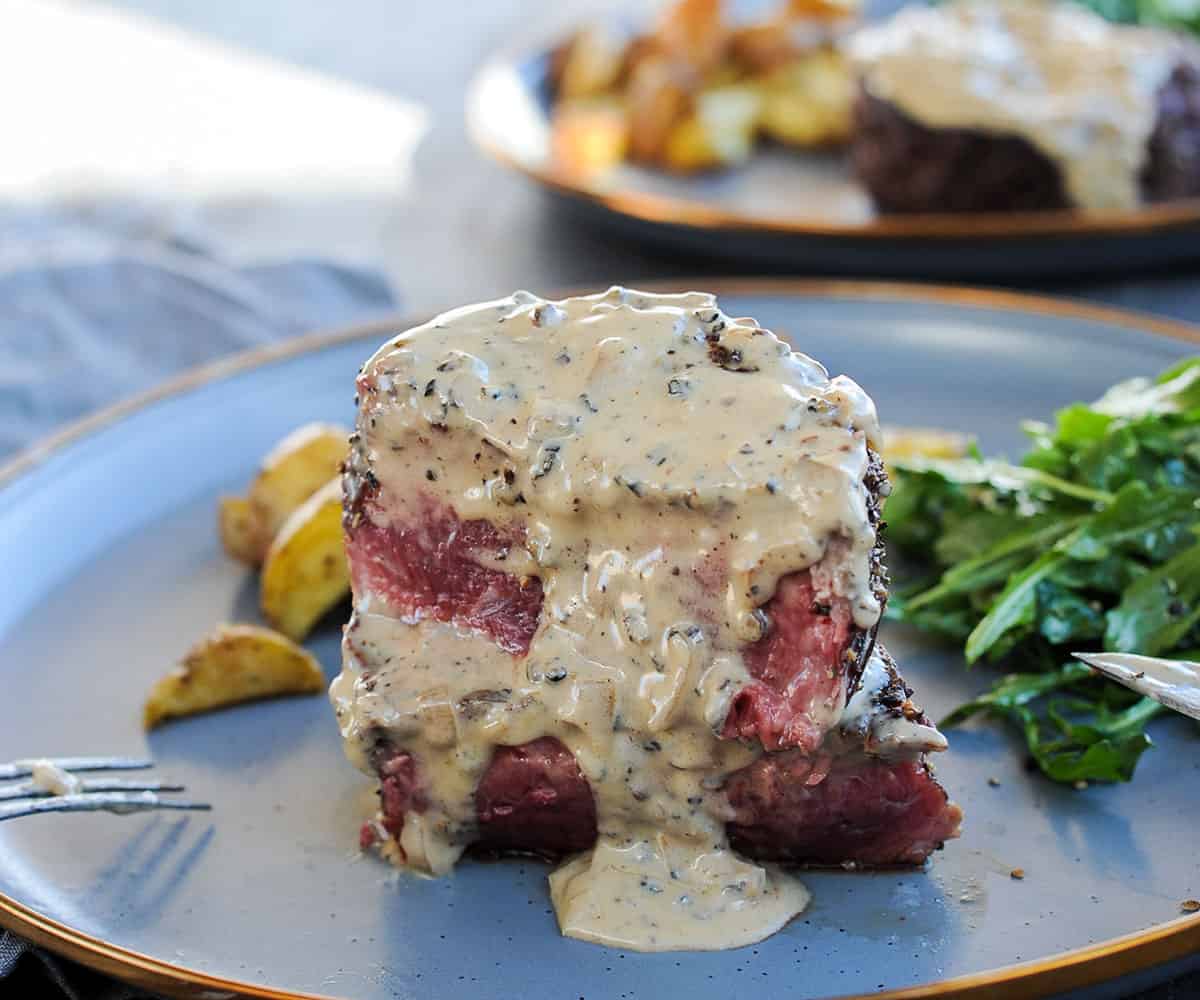 sliced filet mignon steak with peppercorn sauce drizzled on top.