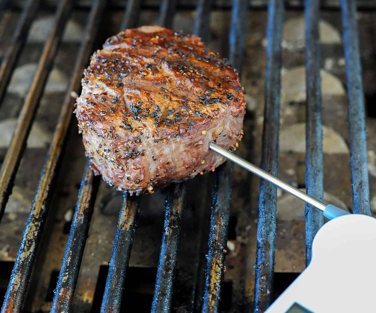 meat thermometer probing steak from side.