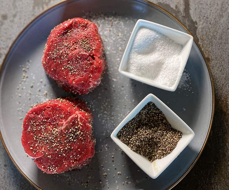 2 raw filet mignon steaks with salt and pepper