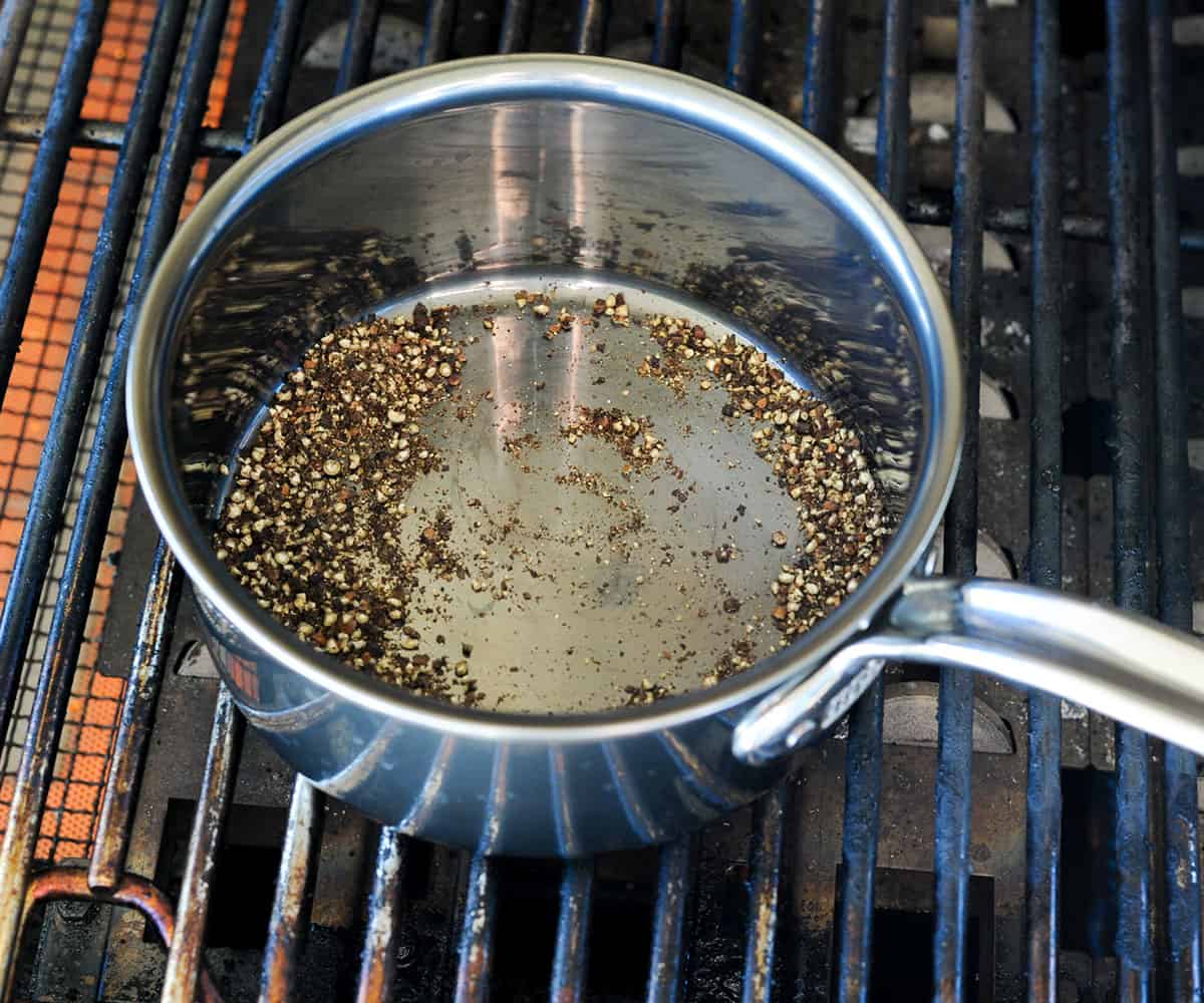 Crushed peppercorns toasting in pot on grill.