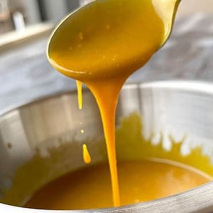 spoon dripping carolina mustard bbq sauce into bowl