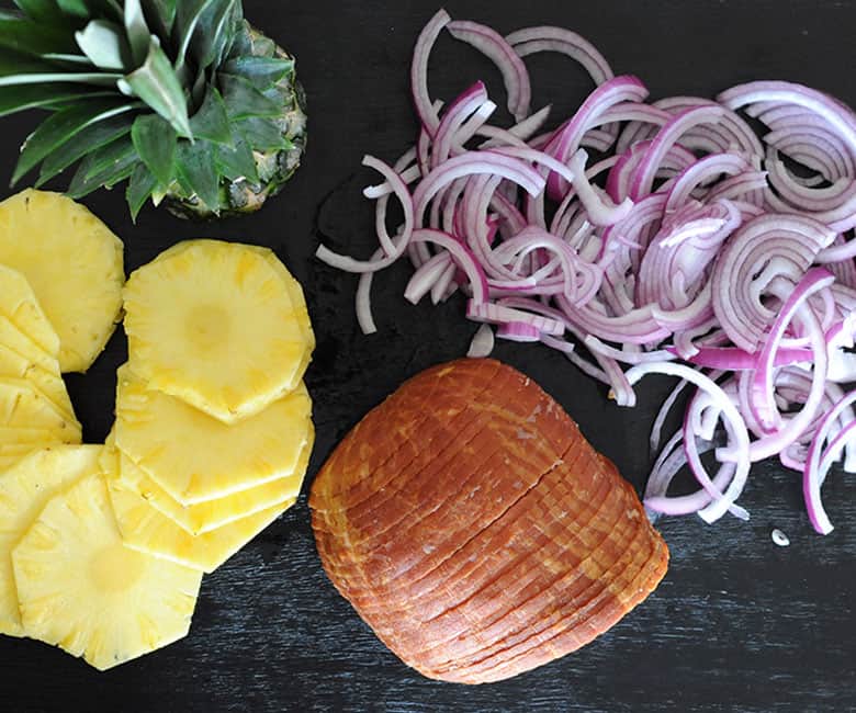 platter of sliced pineapple, red onion and ham for Hawaiian ham sliders