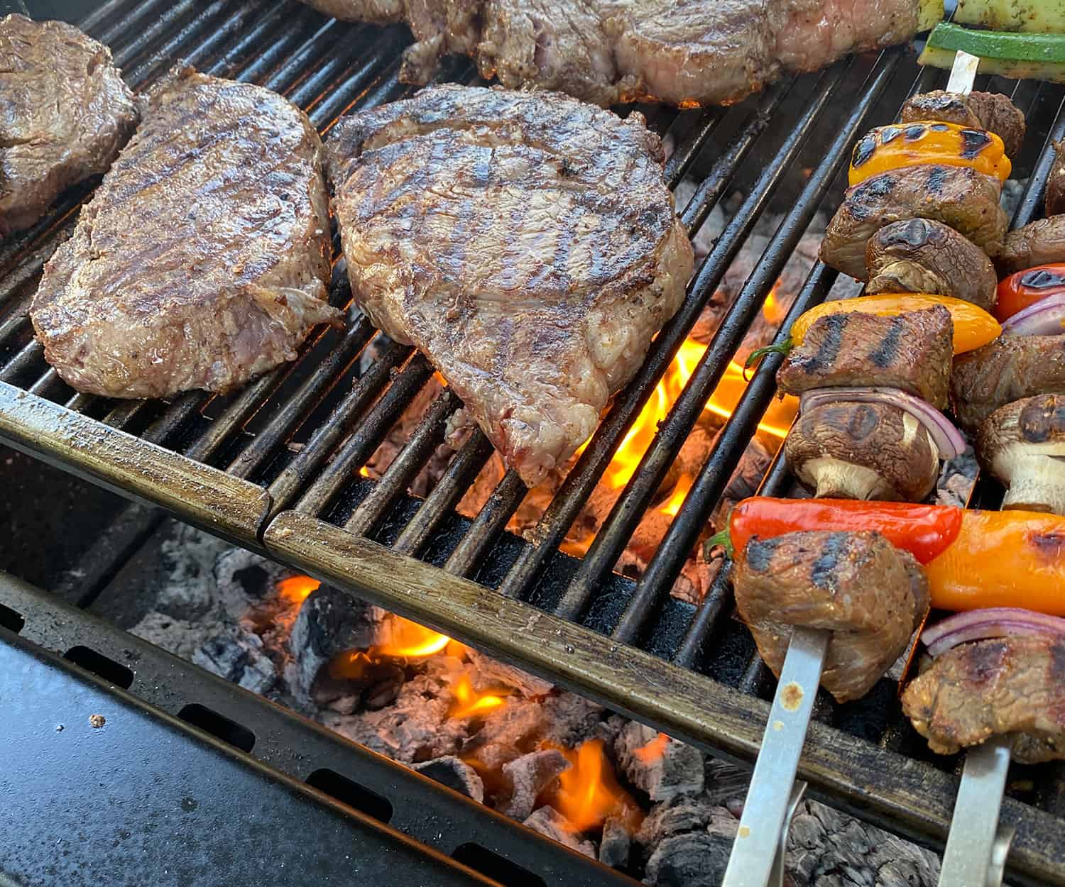 steaks and kabobs grilling over Cowboy Lump Charcoal