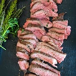 Sliced Santa Maria-style tri-tip on a platter with an herb brush.