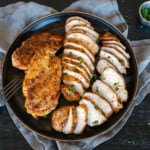 platter of grilled chicken breasts sliced.