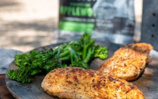plate of two chicken breasts and broccoli by bag of Cowboy Charcoal