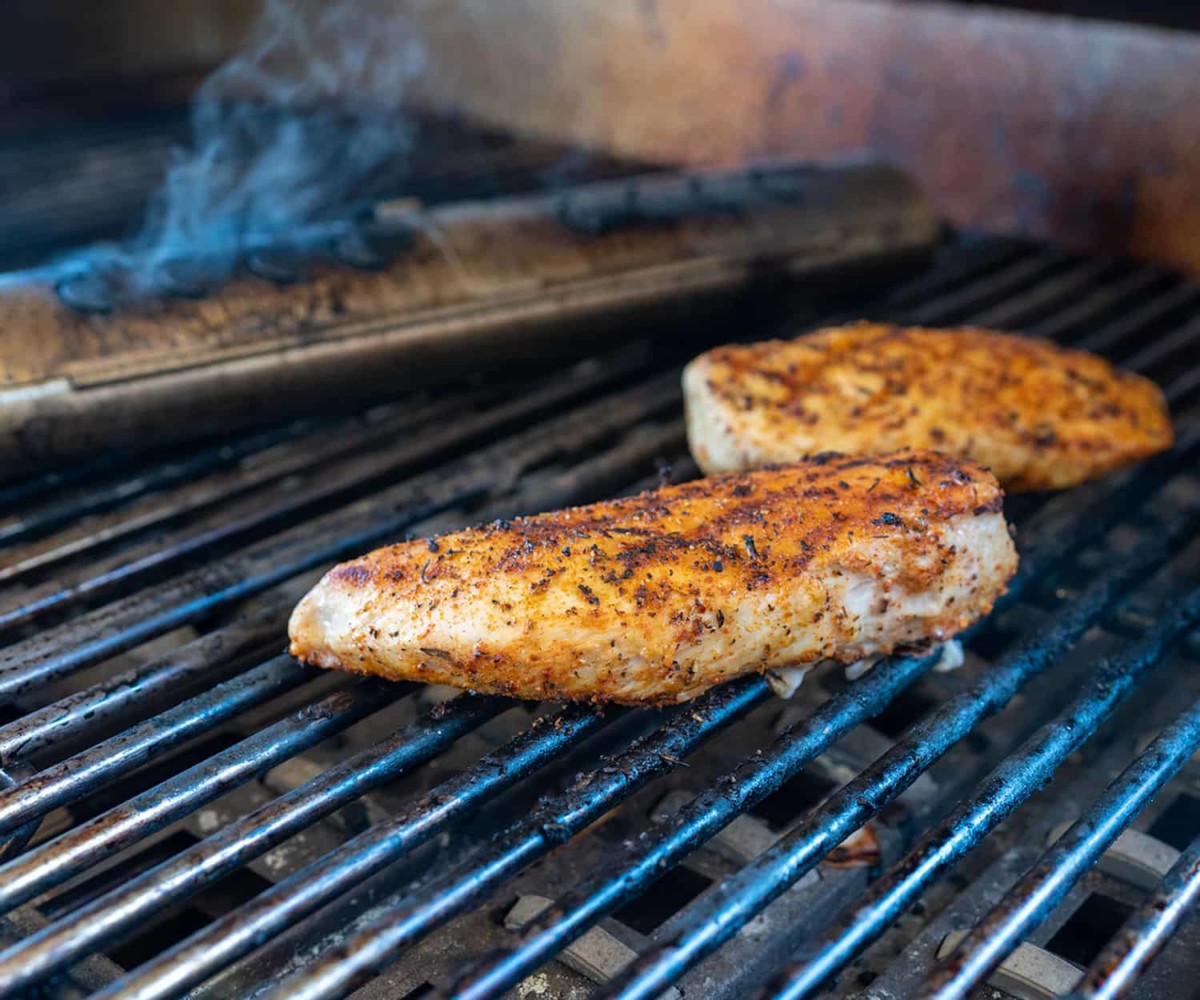 two chicken breasts on gas grill with wood chips