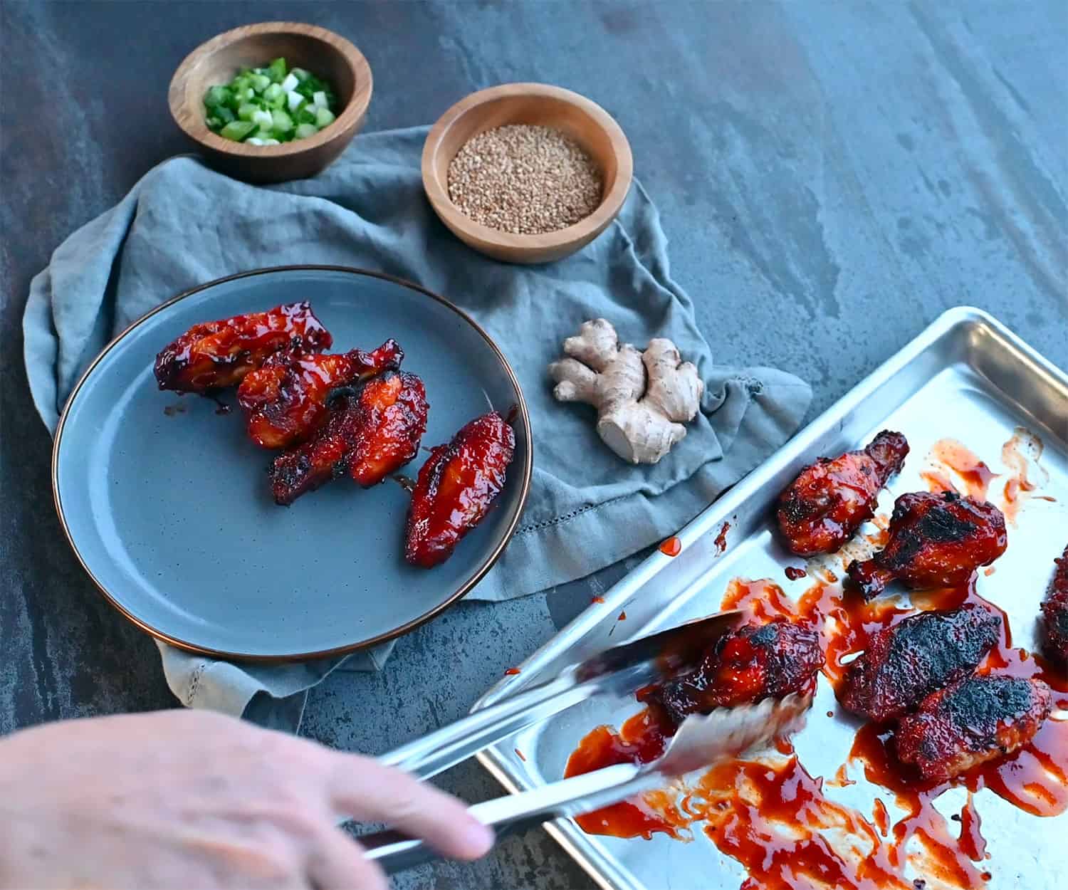 moving Korean chicken wings from pan to plate with tongs