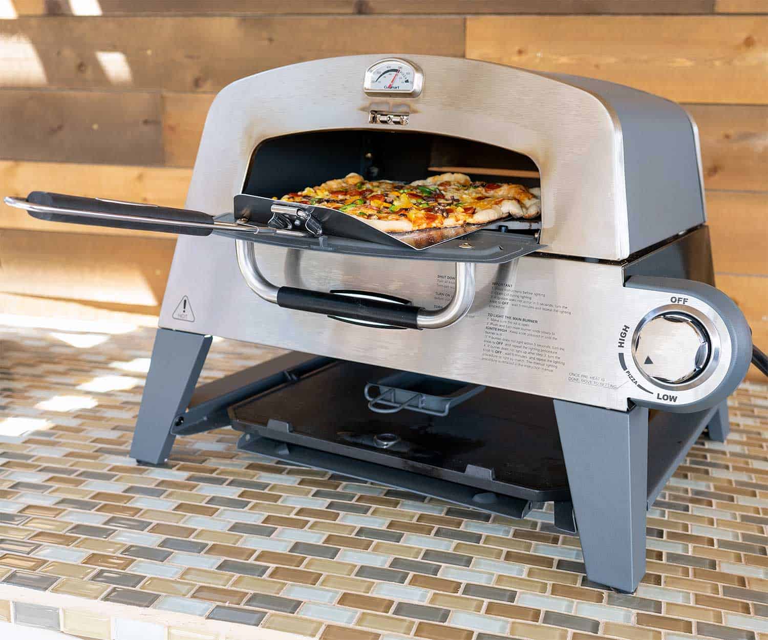 Cuisinart 3-in-1 Pizza Oven Plus with pizza coming out front door on peel.
