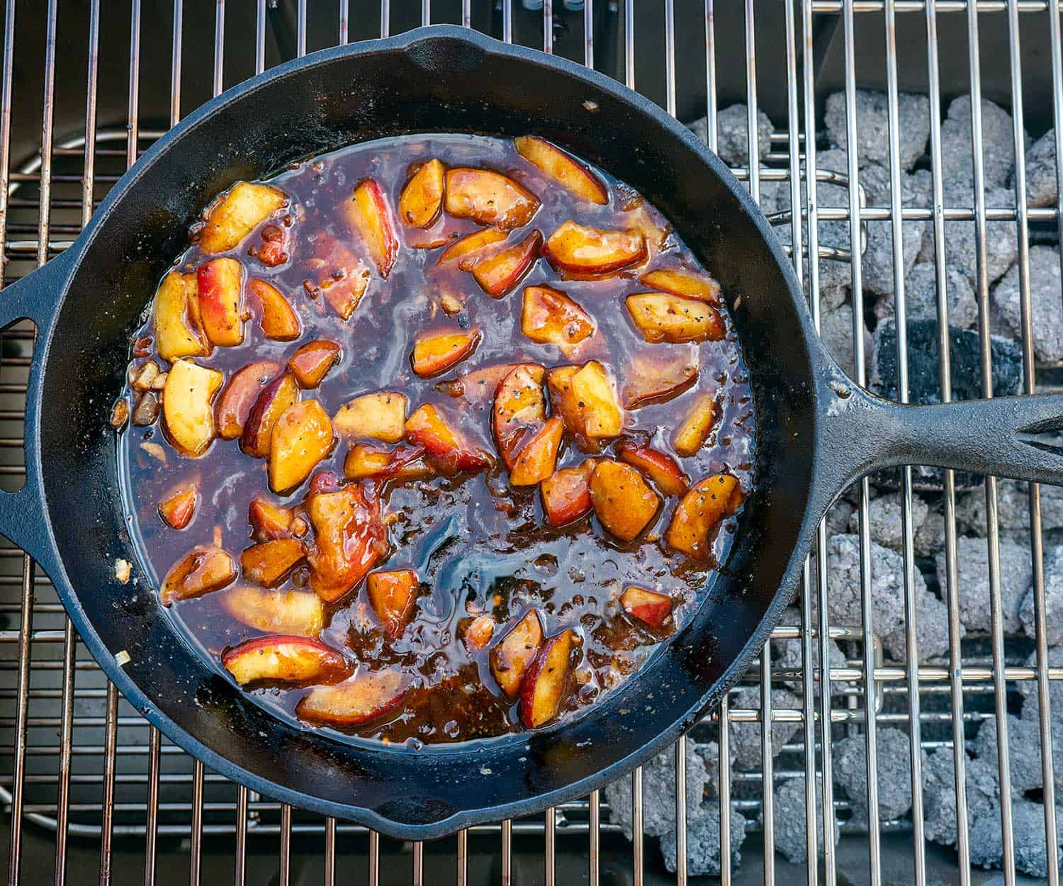 overhead shot of barbecue peaches in cast iron skillet on grill.