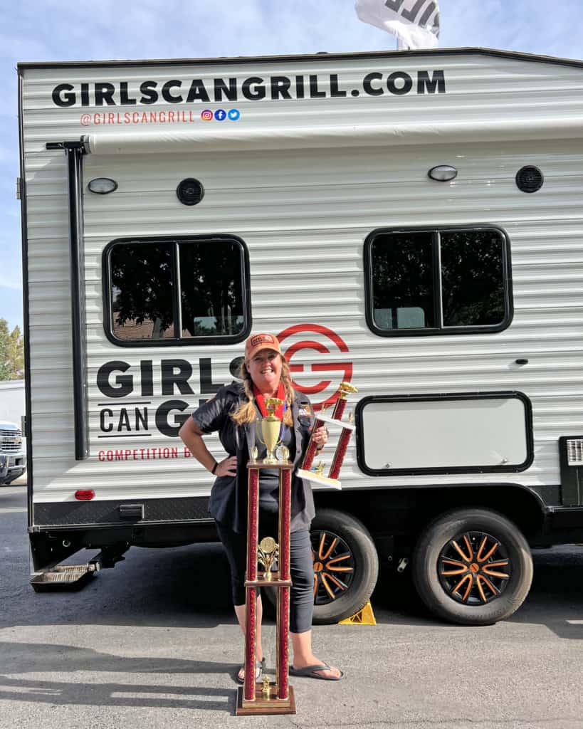 Christie Vanover stands with grand champion trophy by trailer.