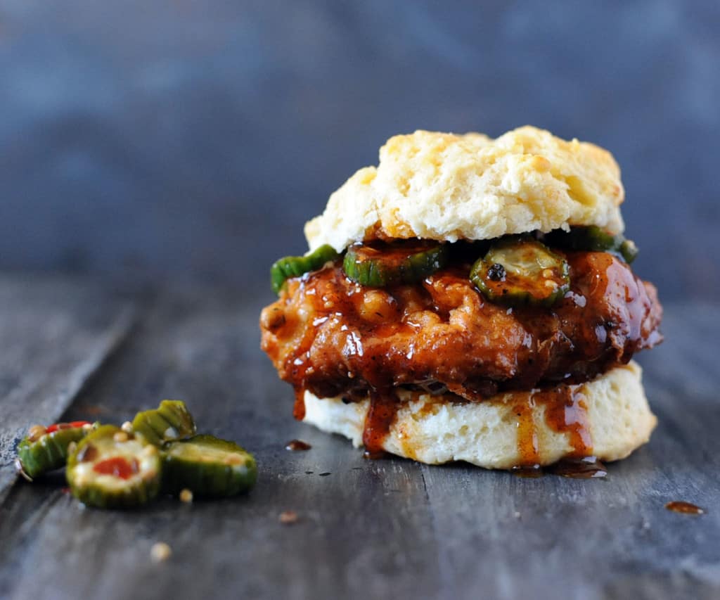 Fried Nashville hot chicken breast on biscuit with pickles.