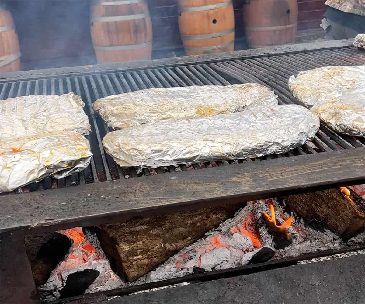 racks of ribs wrapped in foil on grill.