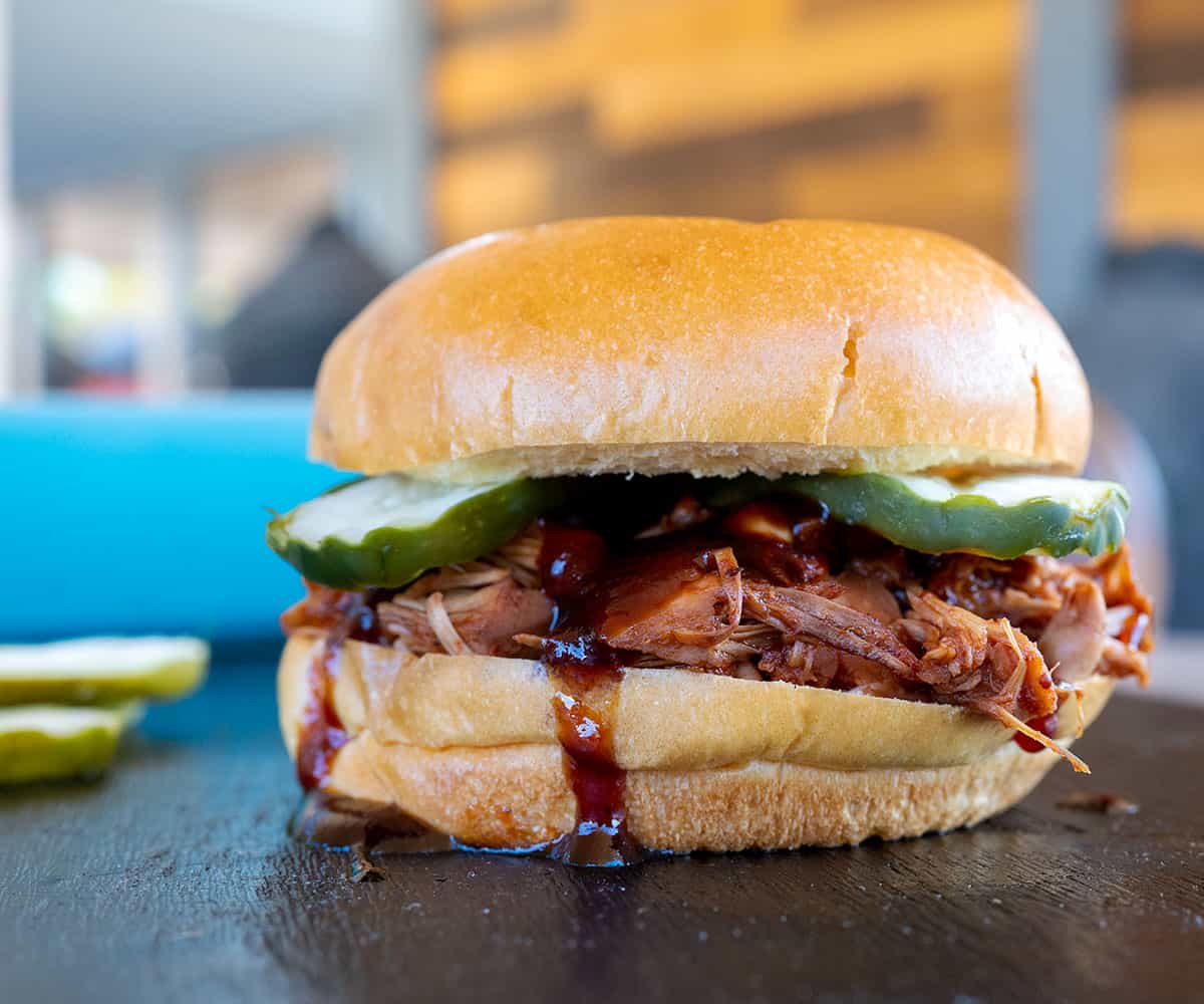 Smoked bbq jackfruit piled on a brioche bun with BBQ sauce and pickles.