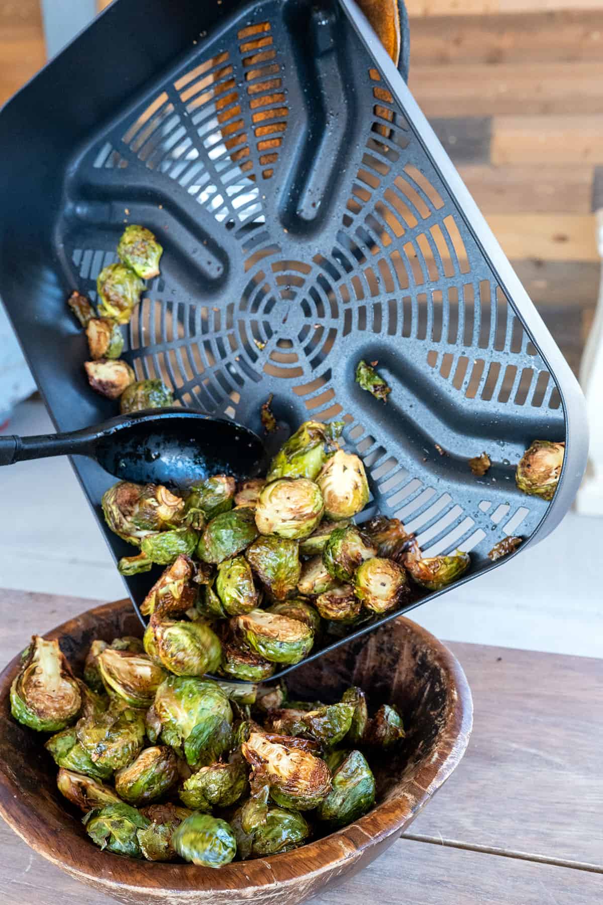Dumping brussels sprouts from air crisper basket to bowl.
