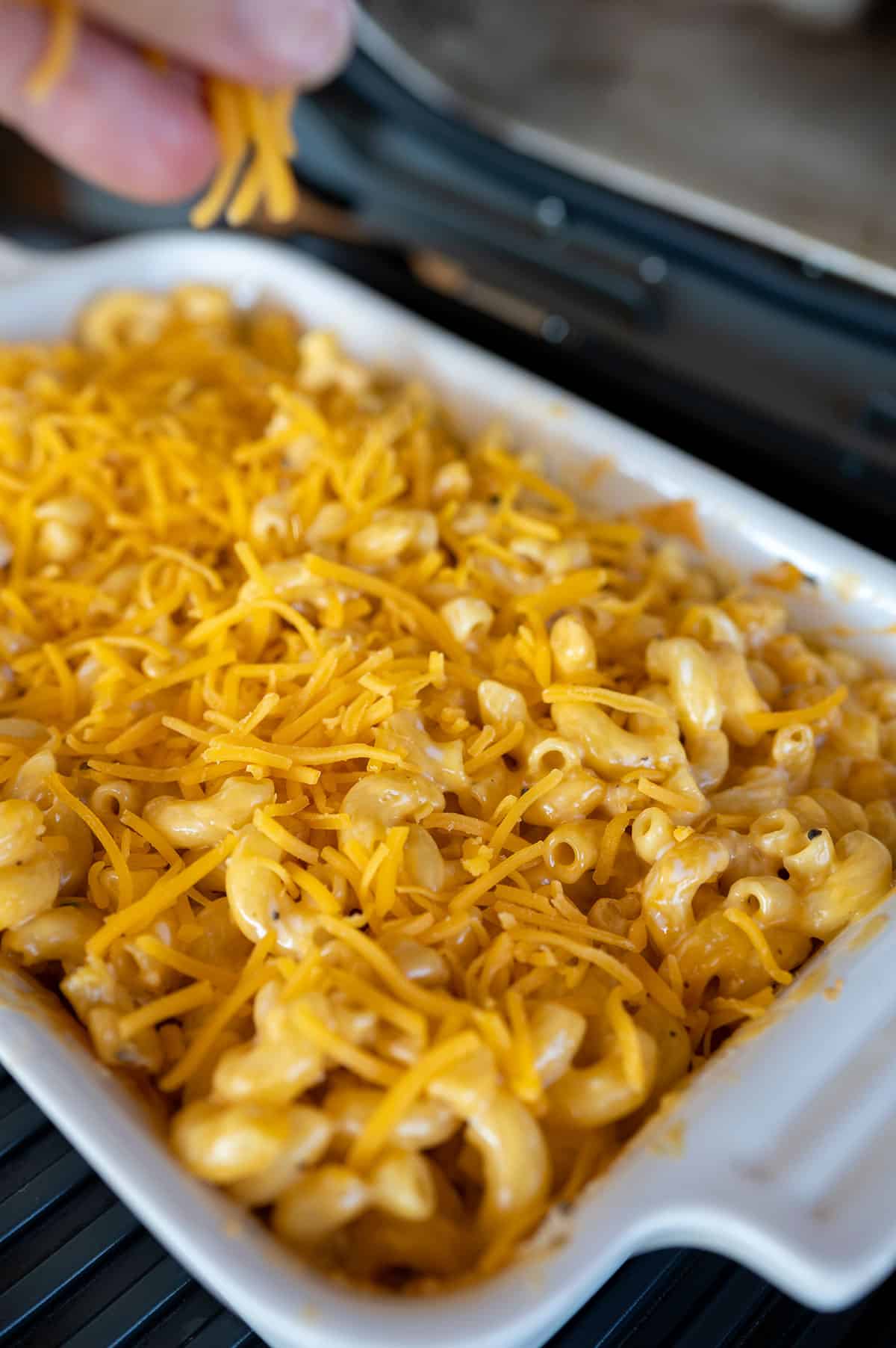 cheddar cheese sprinkled on top of dish of Smoked Mac and Cheese.