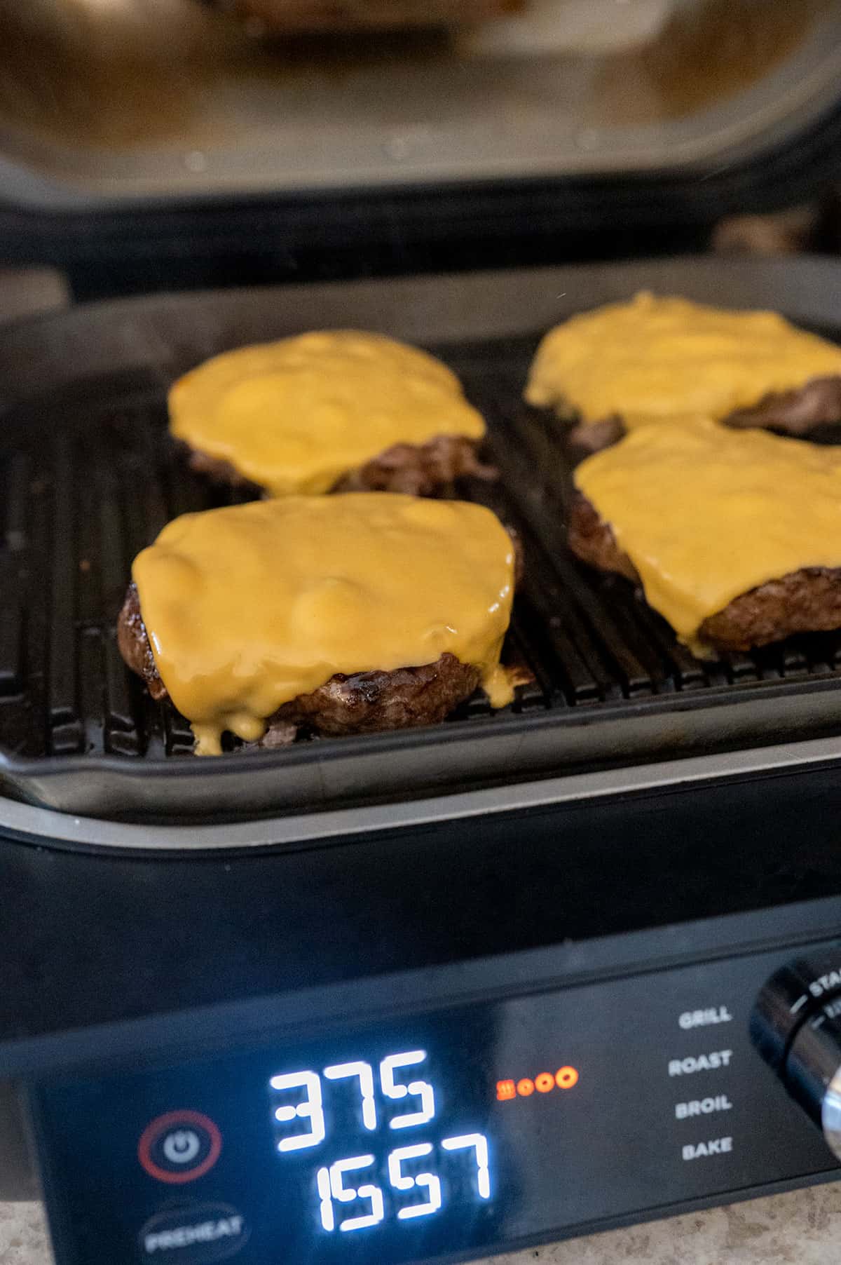 4 burger patties on Ninja Grill with melted American Cheese.